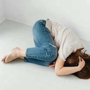 Osoba leżąca bezsilnie na ziemi, symbolizująca stan niezaradności życiowej i braku motywacji do działania.