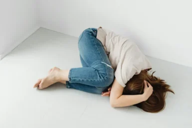 Osoba leżąca bezsilnie na ziemi, symbolizująca stan niezaradności życiowej i braku motywacji do działania.