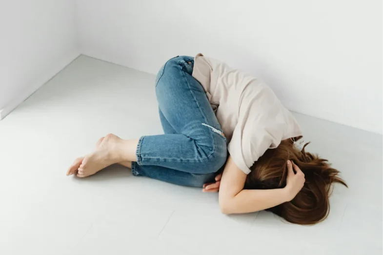 Osoba leżąca bezsilnie na ziemi, symbolizująca stan niezaradności życiowej i braku motywacji do działania.