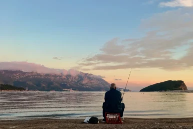 Wędkarz łowiący ryby o wschodzie słońca – relaksujące hobby na świeżym powietrzu.